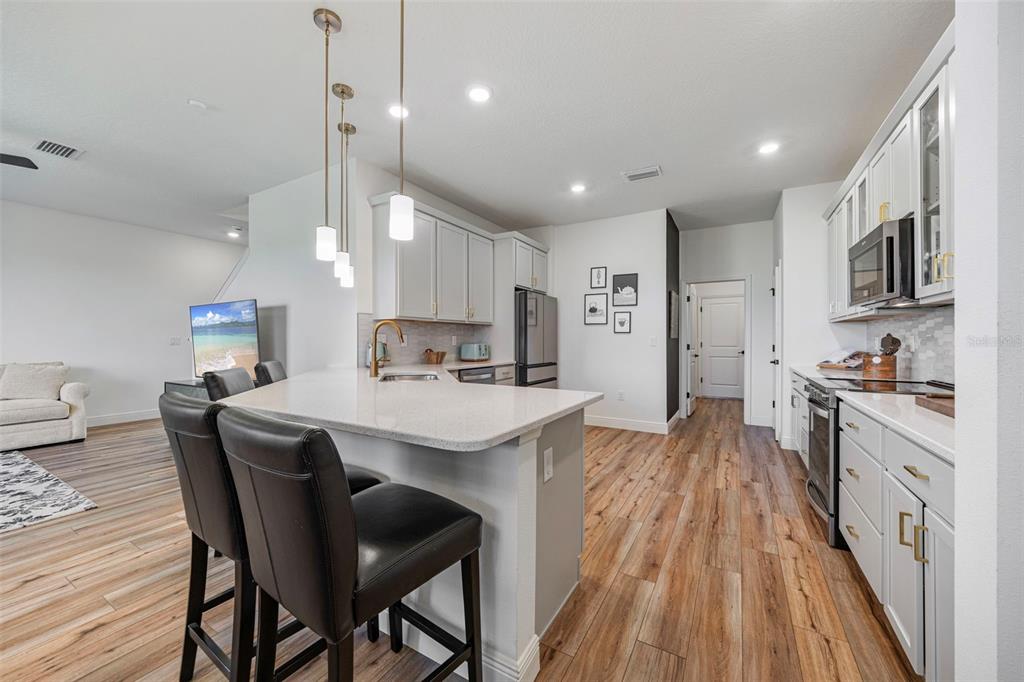 11430 Gallatin Trail Parrish, FL 34219 - Photo 24 of 79 a kitchen with stainless steel appliances a stove a sink a kitchen island with wooden floor and cabinets