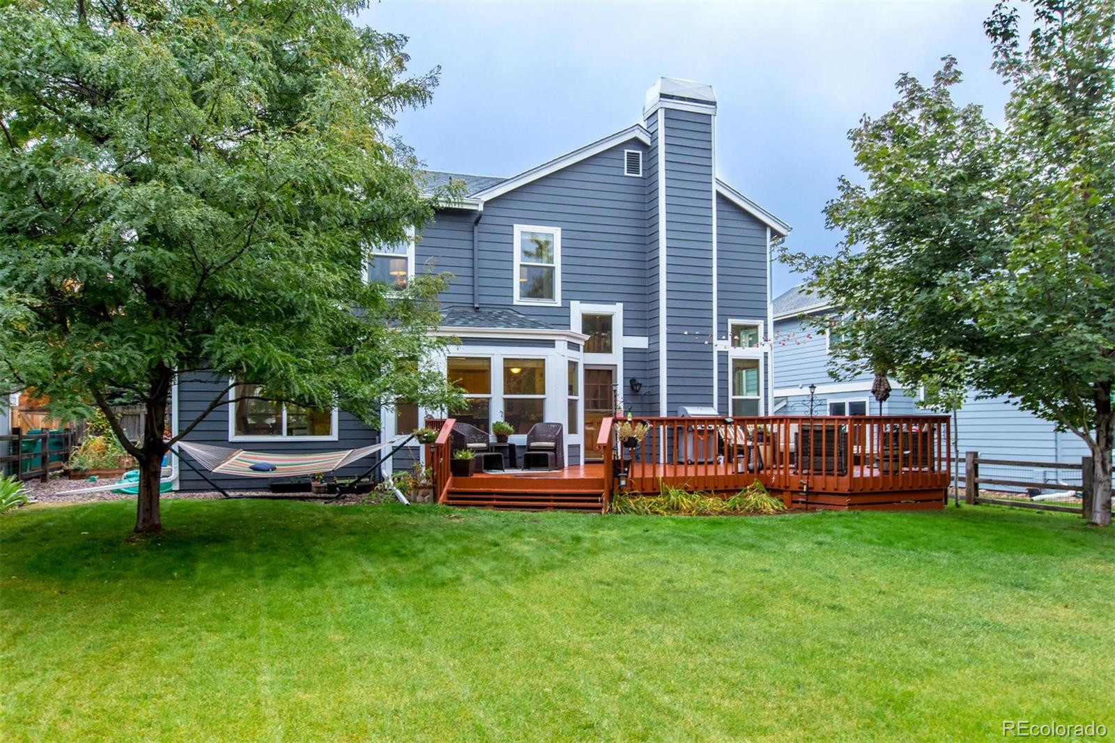 10037 Hooker Street Westminster, CO 80031 - Photo 27 of 40 a front view of a house with garden and a wooden bench