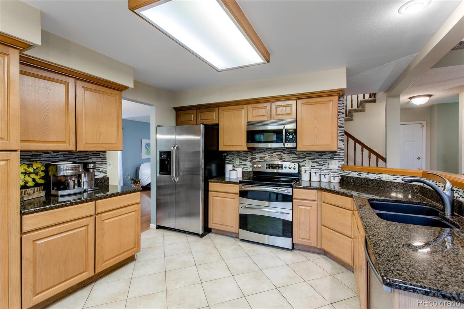 10037 Hooker Street Westminster, CO 80031 - Photo 9 of 40 a kitchen with stainless steel appliances granite countertop a stove sink and cabinets