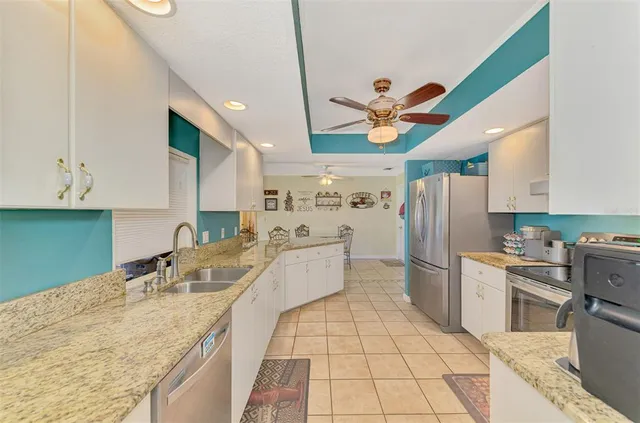 a kitchen with stainless steel appliances granite countertop a refrigerator a stove and white cabinets with wooden floor