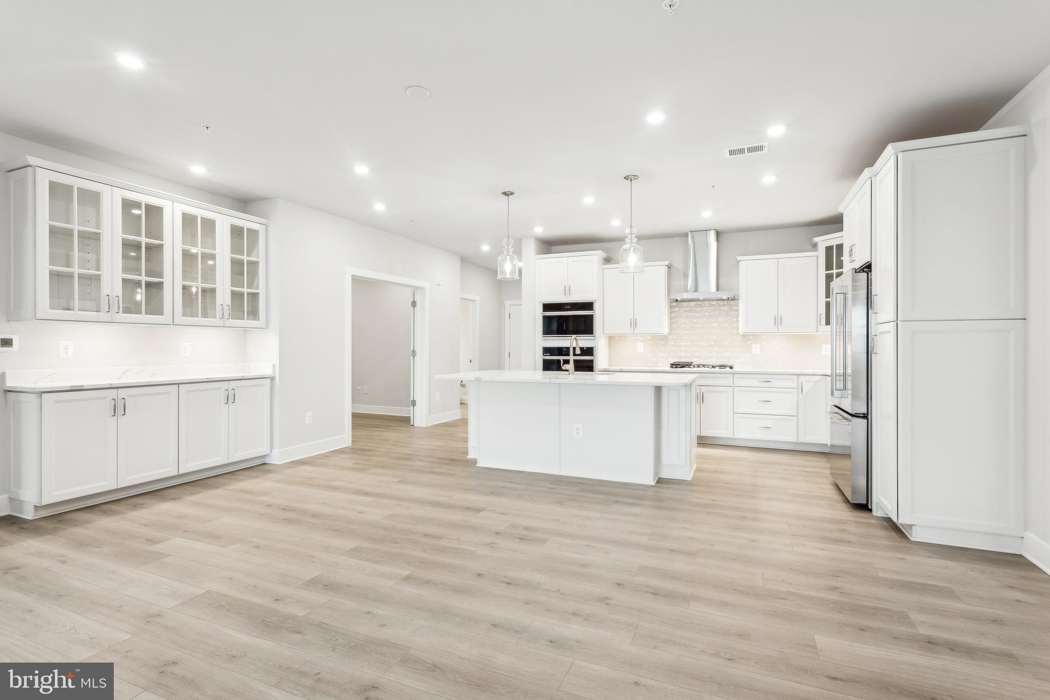 630 Warbler Way, Unit 2212 Chester, MD 21619 - Photo 13 of 73 a large kitchen with kitchen island a stove a refrigerator a white cabinets and wooden floor