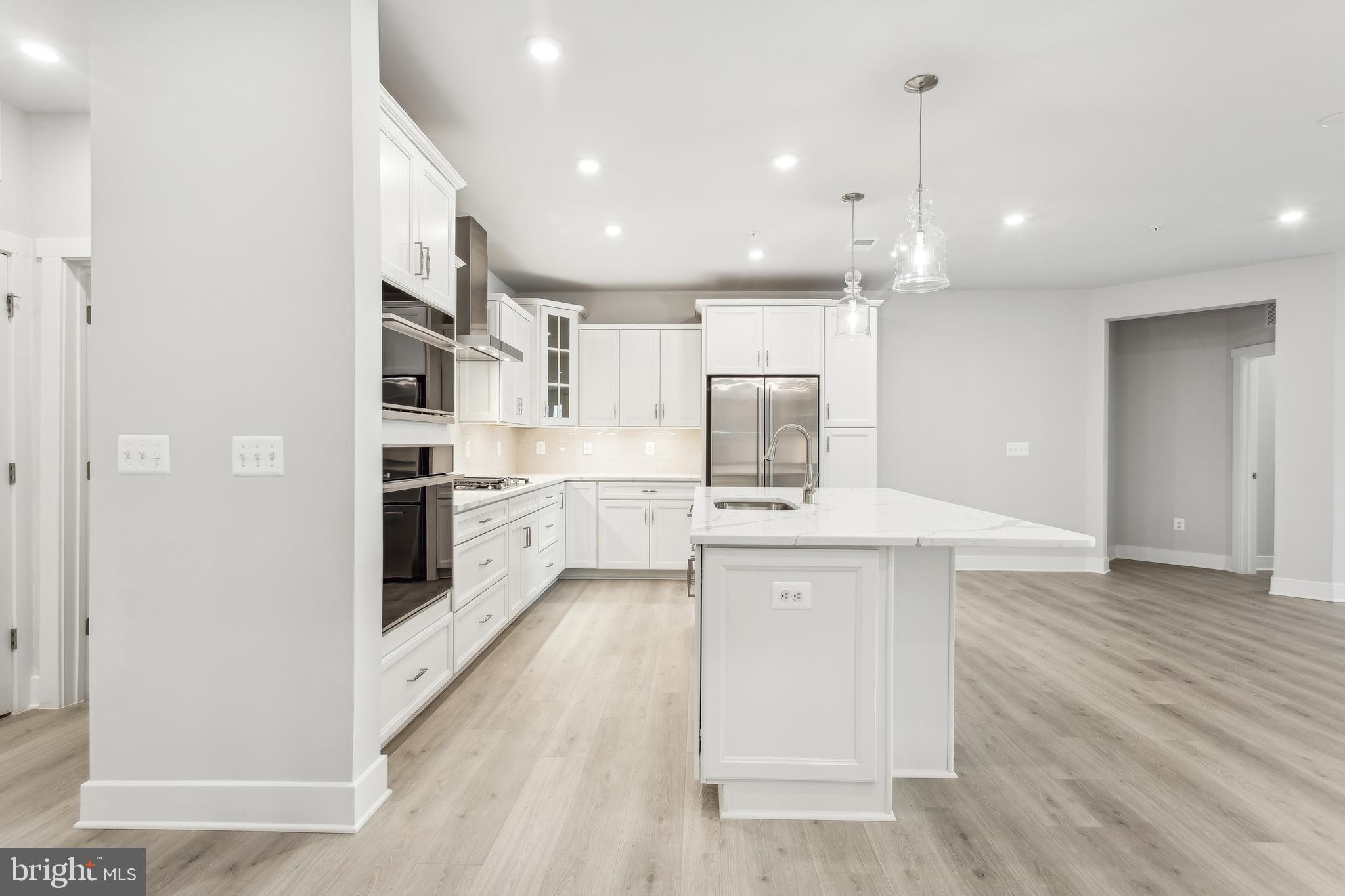 630 Warbler Way, Unit 2212 Chester, MD 21619 - Photo 14 of 73 a kitchen with stainless steel appliances kitchen island a sink dishwasher a refrigerator and white cabinets with wooden floor