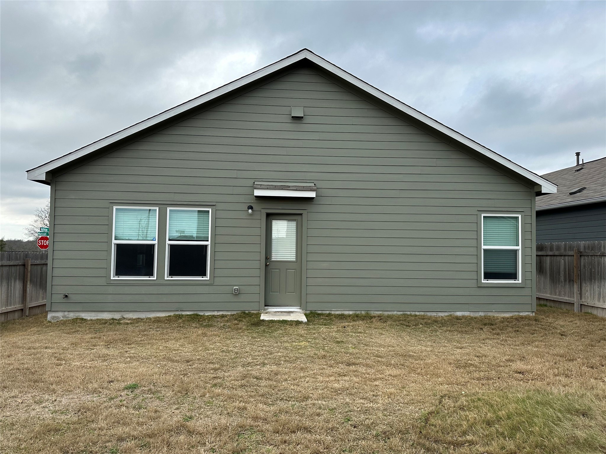 13501 Mussel Run Elgin, TX 78621 - Photo 17 of 28 Rear exterior featuring horizontal siding, a gabled roofline, and multiple windows
