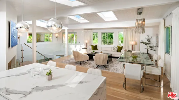 a view of a dining room with furniture a chandelier and large windows