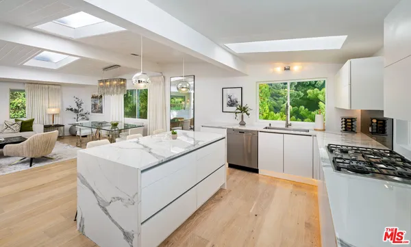 a large white open kitchen with stainless steel appliances kitchen island granite countertop a sink and cabinets