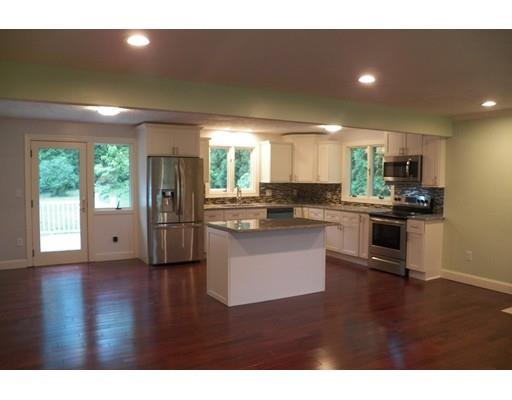 a kitchen with stainless steel appliances granite countertop a refrigerator a sink dishwasher a stove and white cabinets with wooden floor