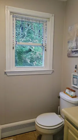 a white toilet sitting next to a window in a bathroom