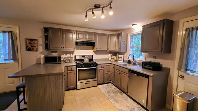 a kitchen with kitchen island granite countertop a sink counter top space appliances and cabinets
