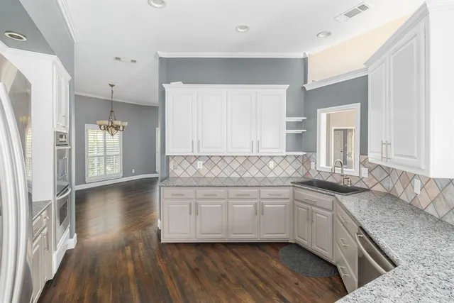 a kitchen with stainless steel appliances granite countertop a sink and cabinets with wooden floor