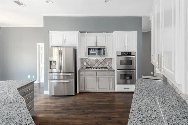a kitchen with granite countertop a refrigerator and a stove top oven