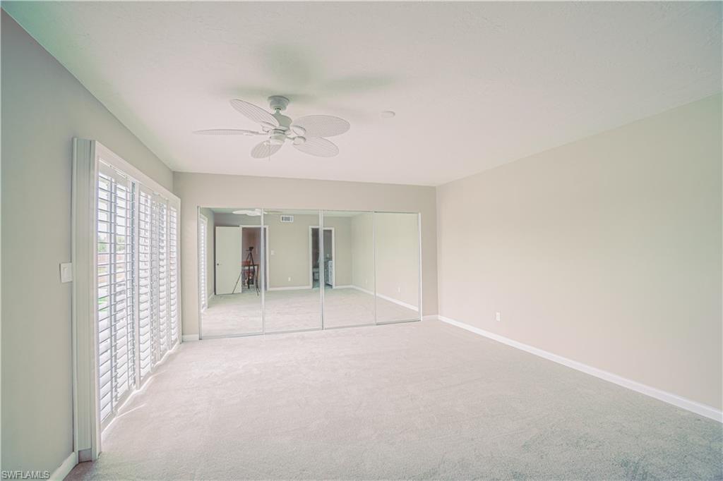 200 Marseille Drive, Unit 12A Naples, FL 34112 - Photo 17 of 36 an empty room with chandelier fan and windows