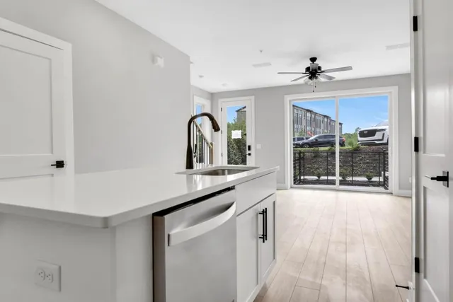 a large kitchen with stainless steel appliances a stove a sink a refrigerator and white cabinets with wooden floor