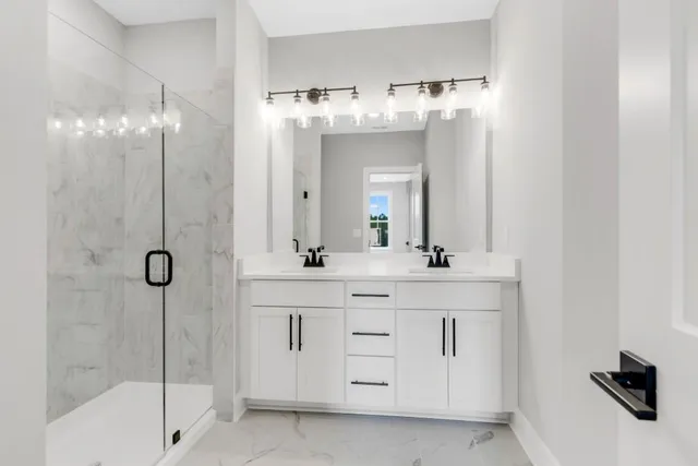 a bathroom with a double vanity sink a mirror a shower and a bathtub