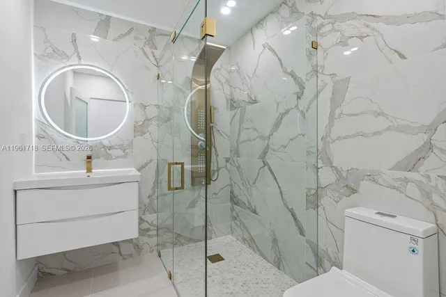 a bathroom with a sink vanity mirror and toilet