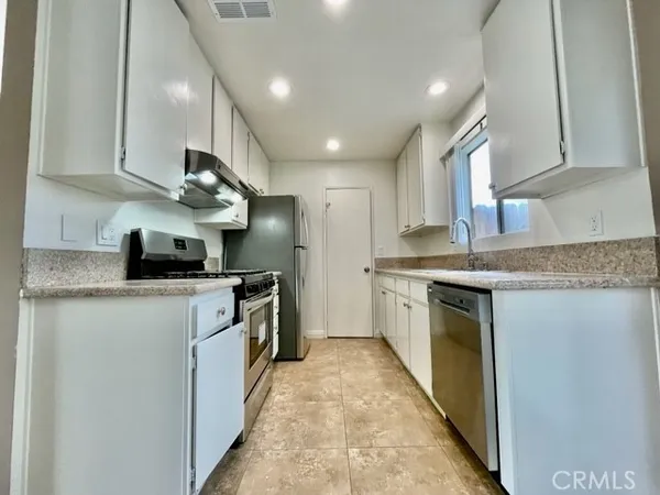 a kitchen with stainless steel appliances granite countertop a sink a stove and a refrigerator