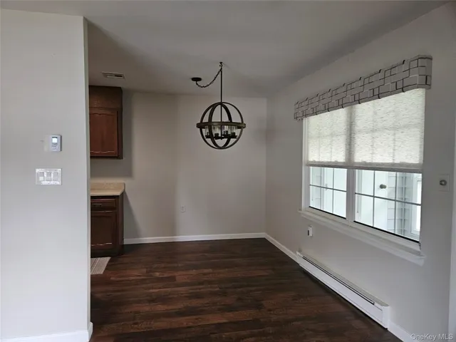 a view of an empty room with wooden floor and windows