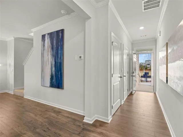 a view of a hallway with wooden floor and a bathroom