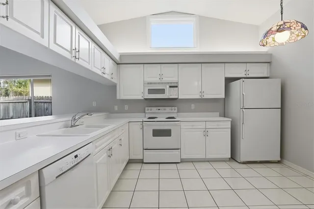 a kitchen with white cabinets appliances a sink and a window