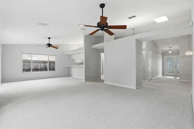 an empty room with chandelier fan and windows