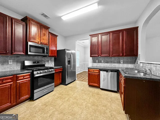 a kitchen with stainless steel appliances granite countertop wooden cabinets a stove top oven a sink and dishwasher