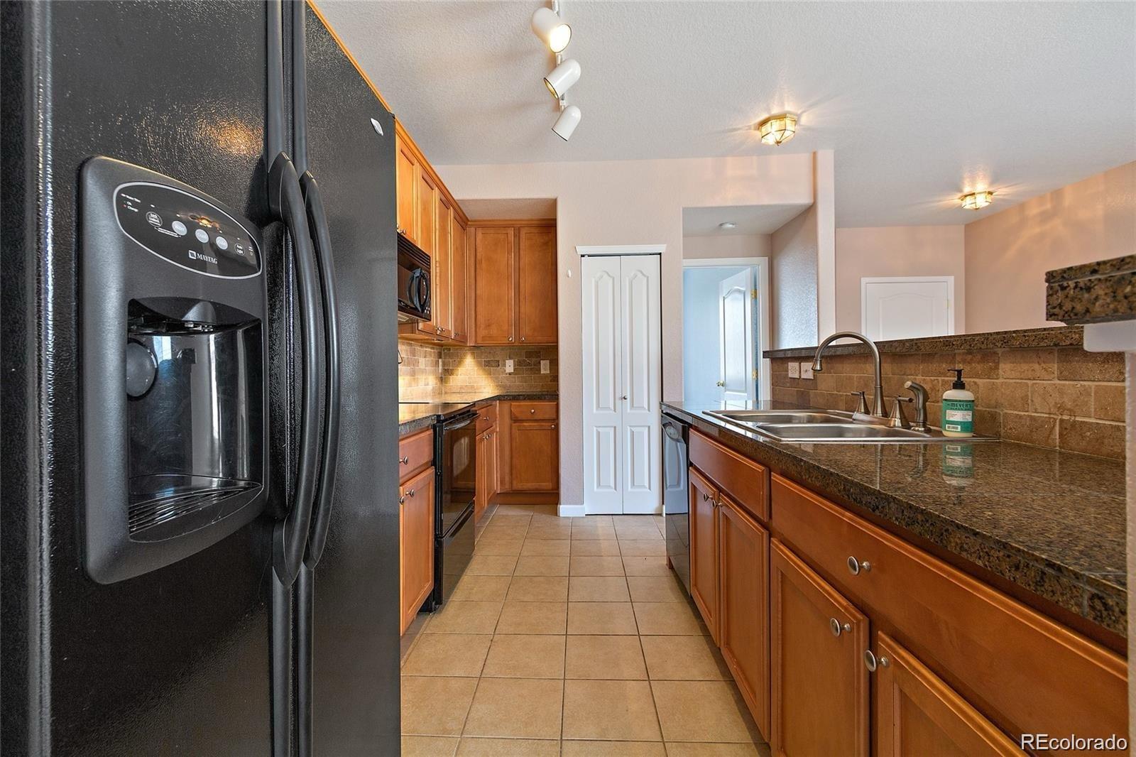 5534 Lewis Street, Unit 206 Arvada, CO 80002 - Photo 11 of 27 a large kitchen with stainless steel appliances granite countertop a refrigerator and a sink