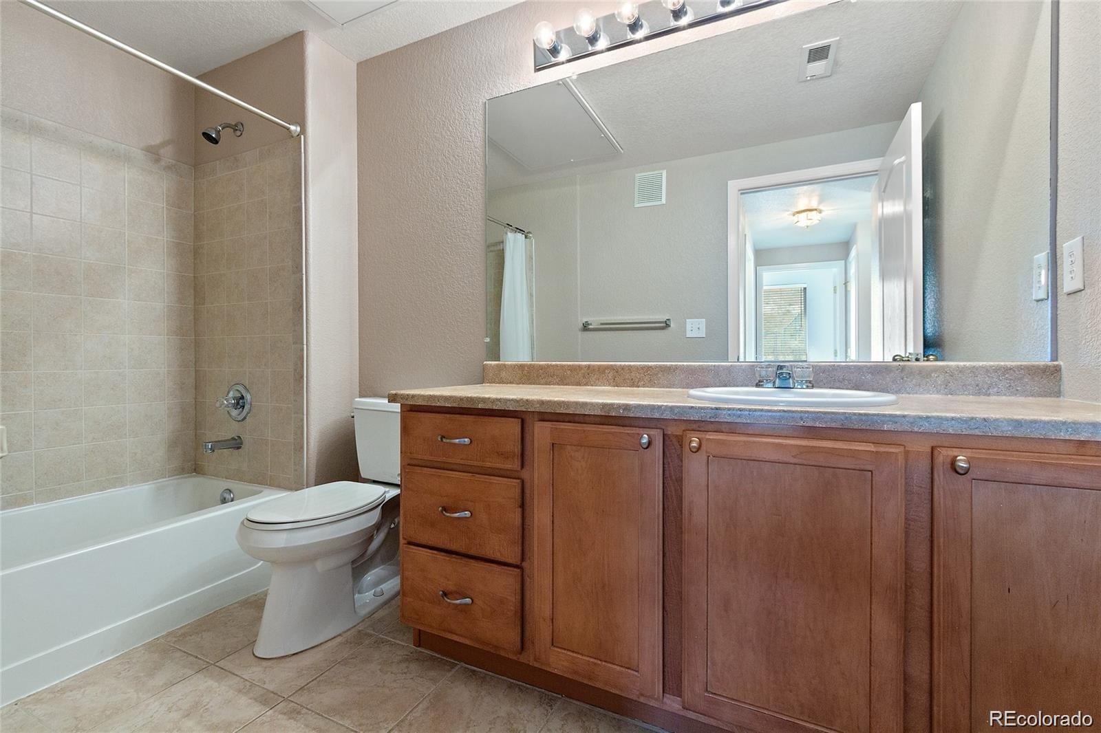 5534 Lewis Street, Unit 206 Arvada, CO 80002 - Photo 21 of 27 a bathroom with a granite countertop sink toilet mirror and bathtub