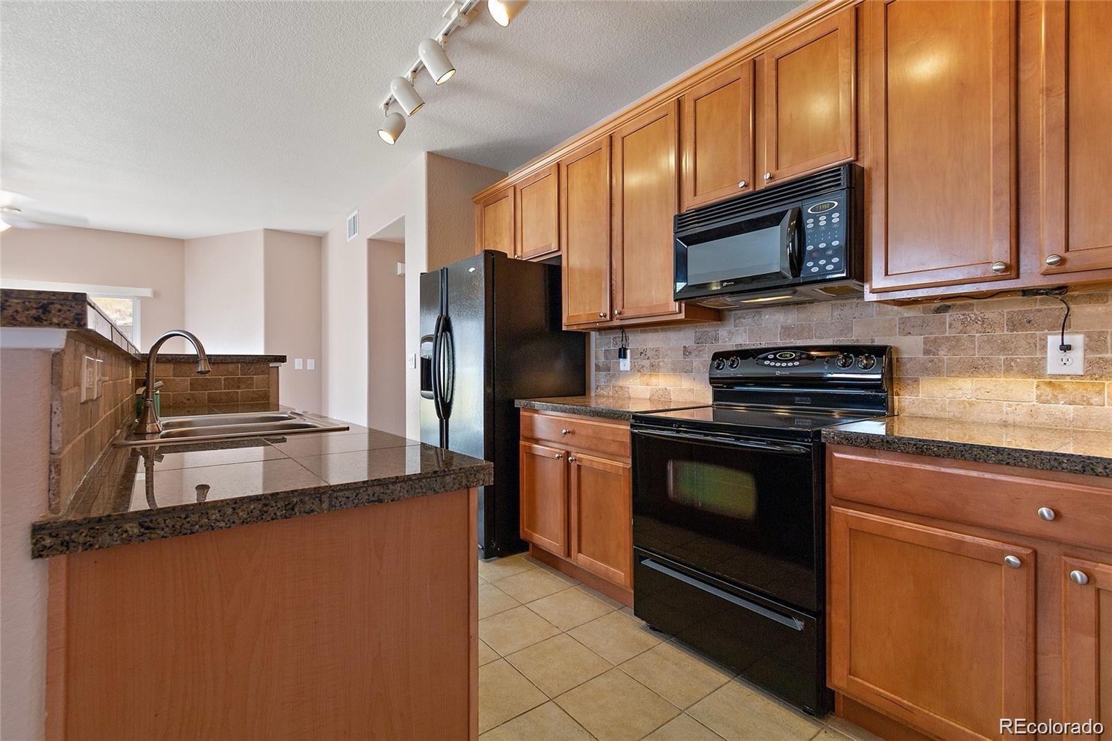 5534 Lewis Street, Unit 206 Arvada, CO 80002 - Photo 10 of 27 a kitchen with stainless steel appliances granite countertop a refrigerator stove microwave and sink