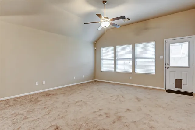 an empty room with chandelier fan and windows