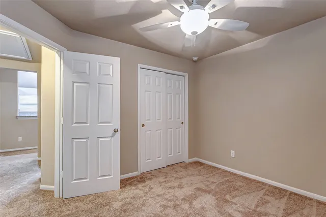 a view of an empty room with a chandelier fan
