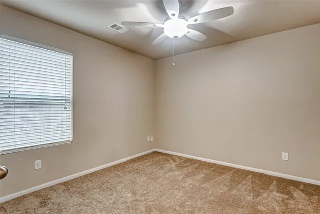en empty room with windows and ceiling fan