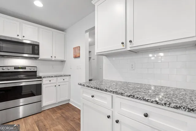 a kitchen with granite countertop white cabinets and stainless steel appliances