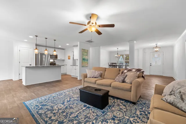 a living room with furniture kitchen view and a chandelier