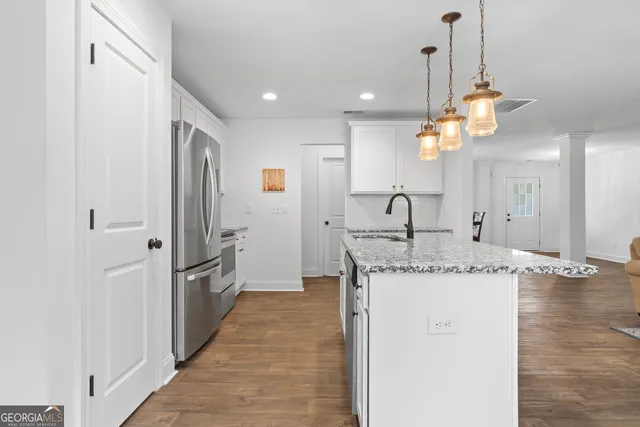 a kitchen with stainless steel appliances granite countertop a sink a refrigerator and a wooden floor