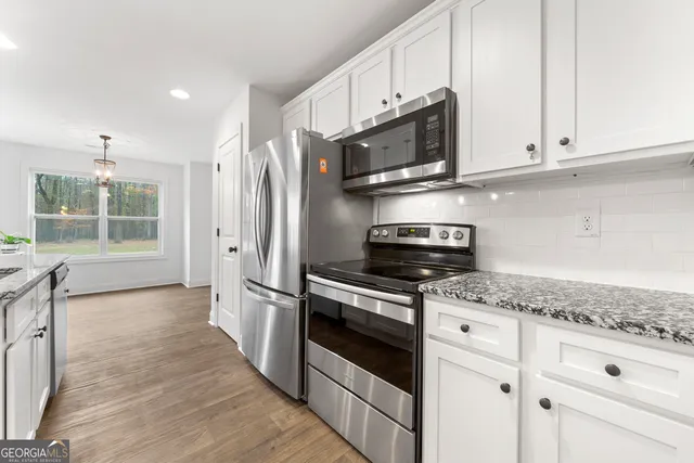 a kitchen with stainless steel appliances granite countertop a stove a microwave and a white cabinets