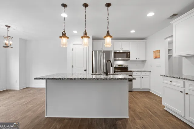 a kitchen with stainless steel appliances granite countertop a sink a stove and a wooden floor