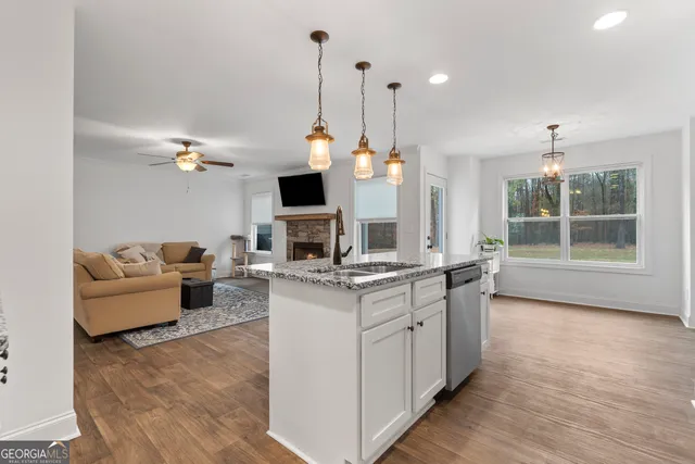 a open kitchen with stainless steel appliances granite countertop a stove and a fireplace with wooden floor