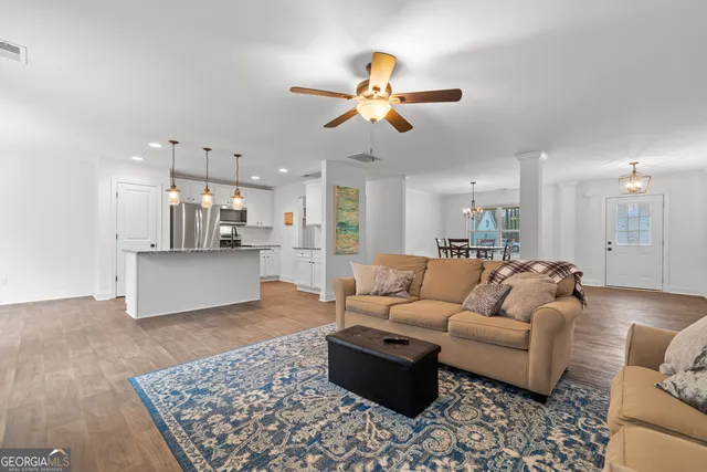 a living room with furniture kitchen view and a chandelier