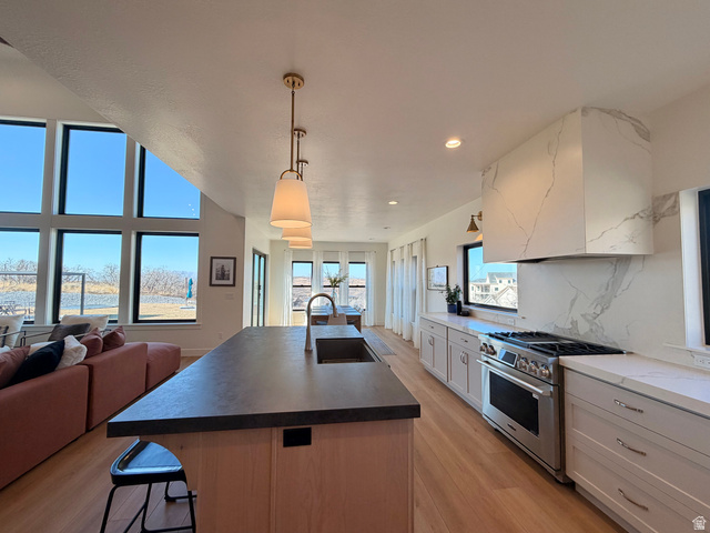3626 Riverstone Road Mapleton, UT 84664 - Photo 58 of 58 Kitchen with stainless steel gas range oven, an island with sink, tasteful backsplash, light wood finished floors, and open floor plan
