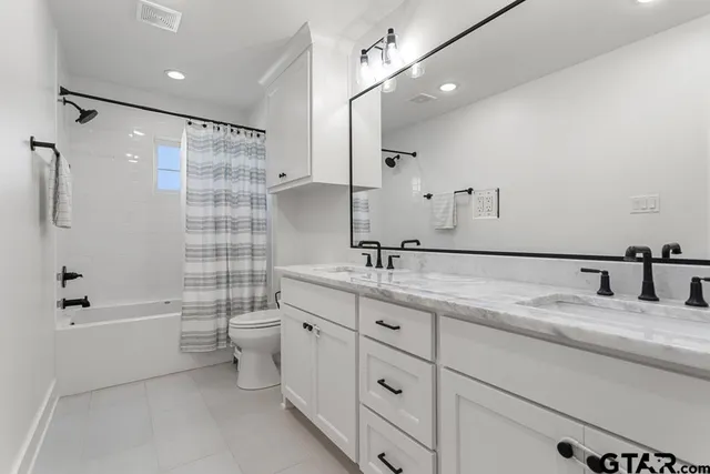 a bathroom with a double vanity sink toilet mirror and shower