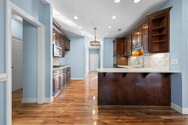 a open kitchen with stainless steel appliances granite countertop a refrigerator a sink and wooden cabinets