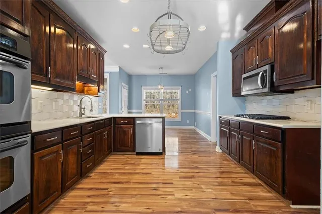 a kitchen with stainless steel appliances granite countertop wooden cabinets a stove top oven a sink and dishwasher