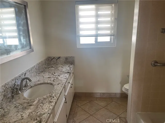a bathroom with a granite countertop sink a toilet and a window