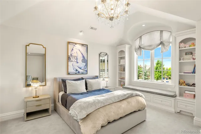 a spacious bedroom with a large bed and a chandelier
