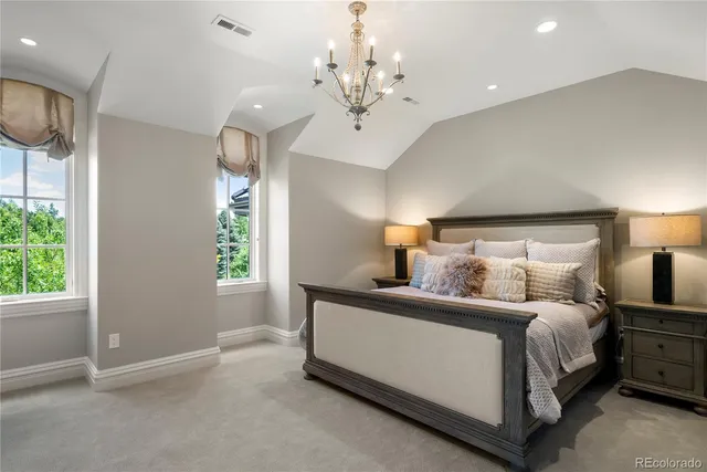 a bedroom with bed a chandelier and a window