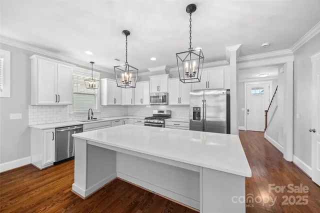 a large kitchen with sink a refrigerator and wooden floor