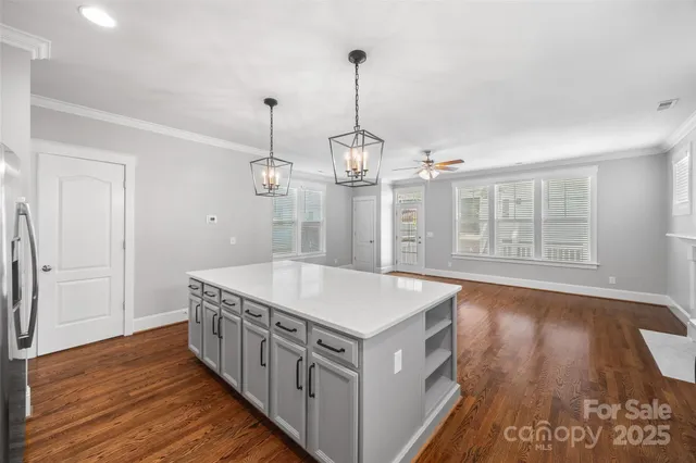 a hall with kitchen island a stove a wooden floor and a window
