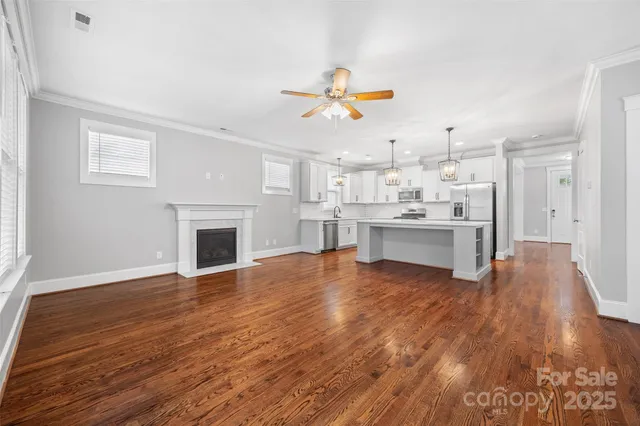 a view of kitchen and empty room with wooden floor