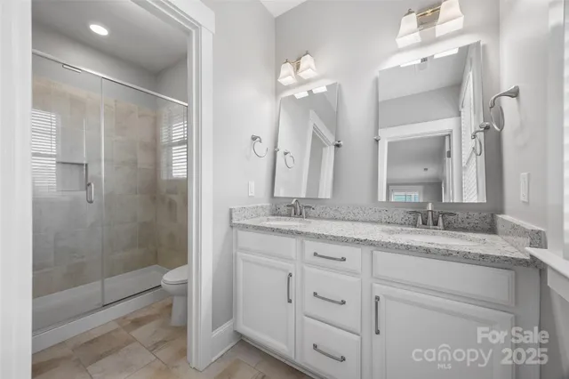 a bathroom with a granite countertop sink a mirror and a shower