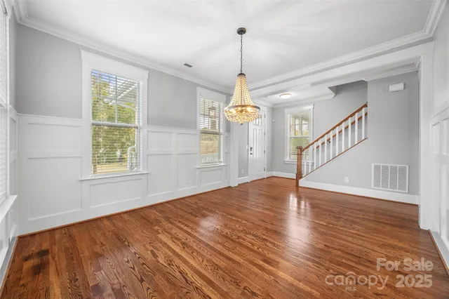 a view of an empty room with wooden floor fridge and a window