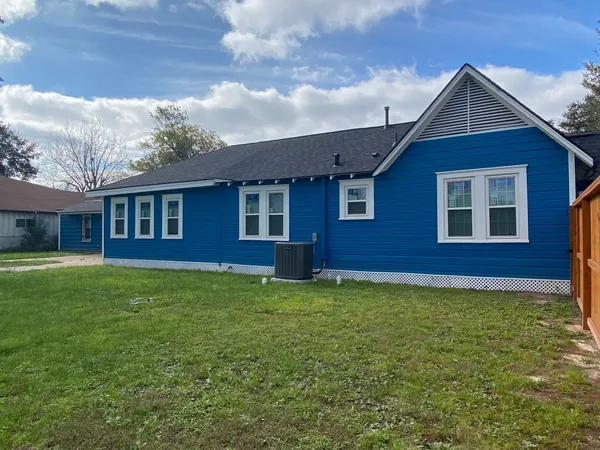 a view of house with a big yard and large trees